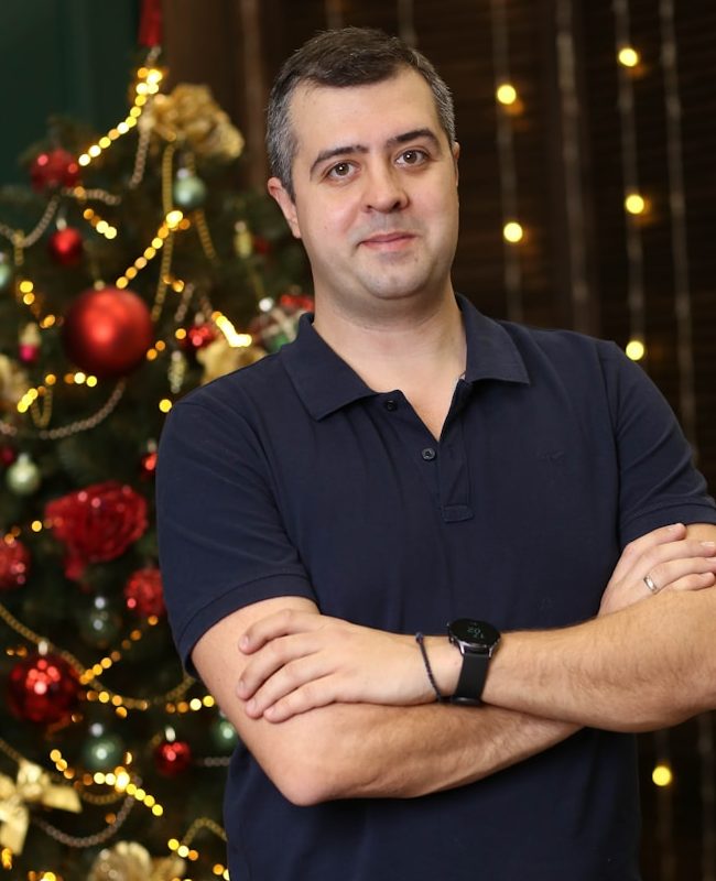 a man standing in front of a christmas tree